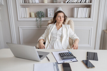 A business lady is sitting at a desk in a bright office. The plot of a tense situation, problems...