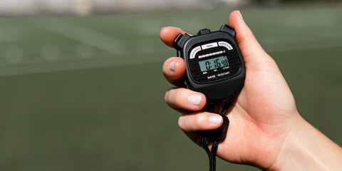 Hand holding digital stopwatch outdoors