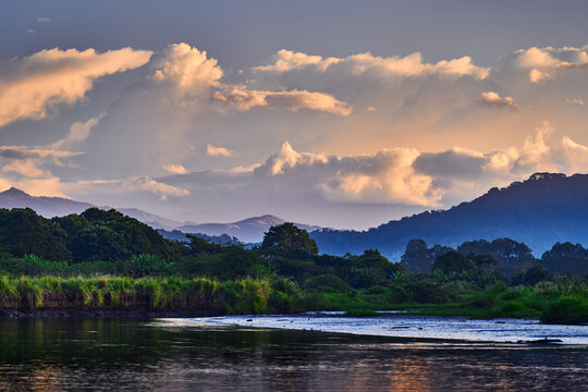 Rio Tarcoles, Carara National Park, Costa Rica. Sunset in beautiful tropical forest landscape. Meanders of river Tarcoles. Hills with orange evening sky. Holiday in Costa Rica. Mountains and clouds.