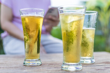 Close-up of hands holding a cold beer glass, condensation forming on the surface, capturing a moment of relaxation, enjoyment