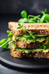 Healthy vegan sandwich with avocado, sprouts and spinach on whole grain bread