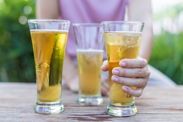 Close-up of hands holding a cold beer glass, condensation forming on the surface, capturing a moment of relaxation, enjoyment