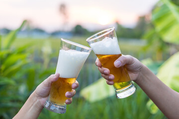 Close-up of hands holding a cold beer glass, condensation forming on the surface, capturing a moment of relaxation, enjoyment
