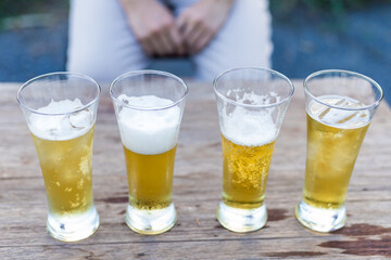 Close-up of hands holding a cold beer glass, condensation forming on the surface, capturing a moment of relaxation, enjoyment