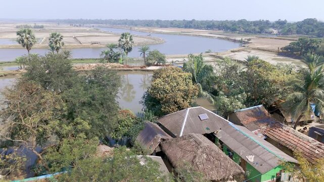 Aerial View of a small Munda village in Shyamnagar, Satkhira, coastal area of Bangladesh. The village is right at the bank of Chuna river. There are vast fields of corps and shrimp culture.