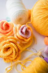 Colorful crochet flowers with yarn and hooks on white background