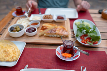 Traditional Turkish breakfast spread with fresh bread, olives, cheese, tomatoes, cucumbers, and variety of jams and spreads. Enjoyed in vibrant setting, capturing essence of Turkish morning culture.