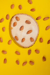 Stylish props and almonds seed on yellow background