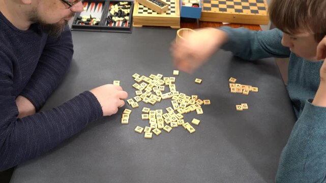 Board game scrabble. Players hands on table take letters. Family fun. Father and son spend time together. Different games