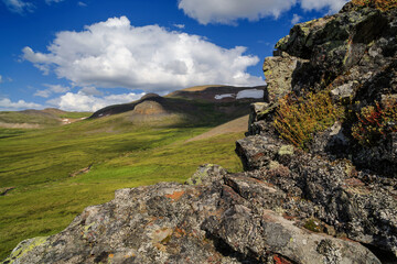 Summer Arctic landscape. Rocks in the foreground. Mountains and tundra in the distance. Travel and ecotourism in the wild. Northern nature of Siberia. Ushkany Ridge, Chukotka, Far East of Russia.