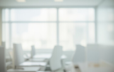Blurred office interior with chairs tables and large window providing natural light.
