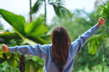 Rear view image of a woman opening arms and do stretching in the garden