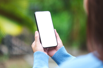 Mockup image of a woman holding mobile phone with blank white desktop screen in the nature outdoors