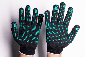 Black safety work glove with green rubber grip dots on white background	