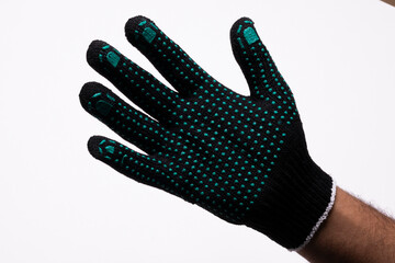 Black safety work glove with green rubber grip dots on white background