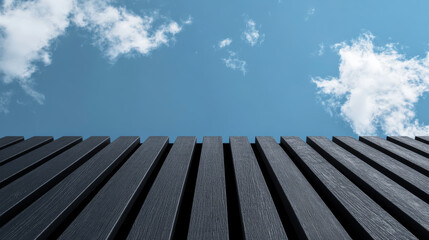 Black wooden slats against blue sky create striking contrast, evoking sense of modernity and tranquility. clouds add depth to serene atmosphere