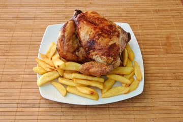 A plate of fried chicken and french fries. The chicken is cut into pieces and is sitting on top of the fries