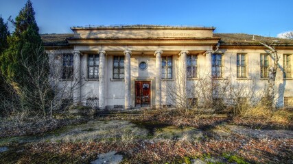 Abandoned neoclassical building in Schonebeck, Germany, with weathered columns and vegetation in...