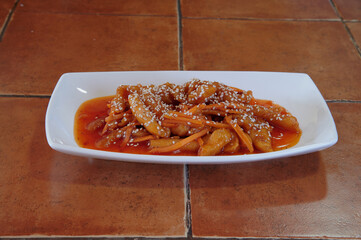 A plate of food with carrots and sauce on it. The plate is white and the food is orange