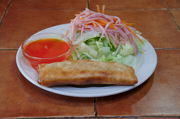 A plate of food with a piece of fried food and a salad. The salad has carrots and ham