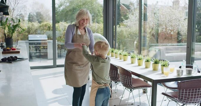 Kitchen, dancing or grandma playing with a happy child laughing with joy in family home together. Cooking breakfast, kid or fun grandmother baking, bonding or holding hands to dance in retirement