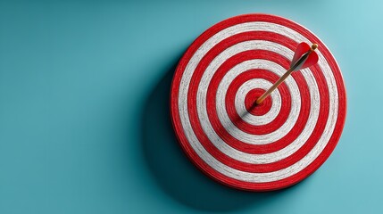 Overhead shot of a red and white target hit by an arrow on a blue backdrop, representing goal achievement and success in business, mockup for design use