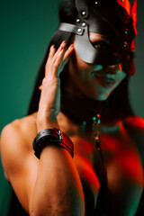 Woman in cat mask and handcuffs striking a pose in neon-lit environment at night