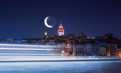 Galata Tower, Galata Bridge, Karakoy district and Golden Horn with motion speed light of passing ferry in the foreground at night istanbul - Turkey  