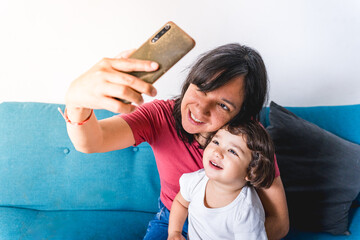 Baby toddler and mother taking a selfie with a mobile phone to share on social media. Concept of...