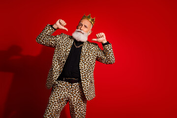Extraordinary elderly man in vibrant leopard print suit celebrating against vivid red background