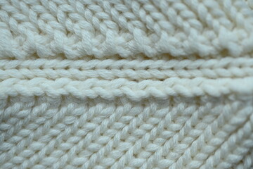white texture of knitted wool fabric as a background, white smooth symmetrical lines of hand-knitted needlework pattern	
