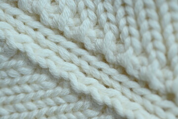 white texture of knitted wool fabric as a background, white smooth symmetrical lines of hand-knitted needlework pattern	
