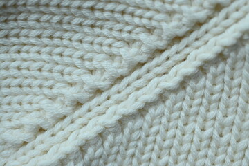white texture of knitted wool fabric as a background, white smooth symmetrical lines of hand-knitted needlework pattern	
