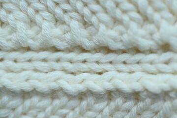 white texture of knitted wool fabric as a background, white smooth symmetrical lines of hand-knitted needlework pattern	
