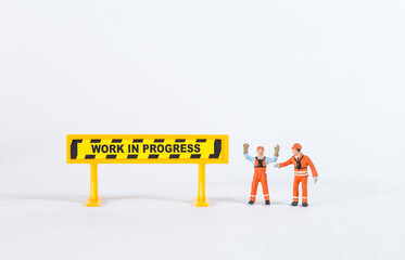 Miniature worker with work in progress sign isolate on white background, construction industry...