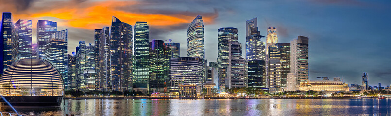 Fototapeta premium Singapore CBD City Skyline on the river at Sunset with vibrant colours of the high-rise apartment and office towers with the beautiful colours of the sky. Panorama view of Singapore CBD buildings 
