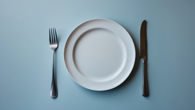 Top-down view of a clean plate, fork, and knife with room for text on background