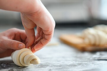 Producing classic croissants at the bakery shop. Woman is rolling dough into rolls for further...