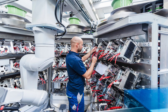 Technician repairing machinery in an automated production hall