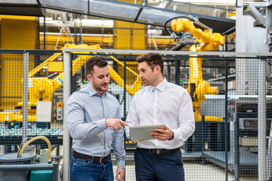 Employees discussing in a production hall with robot arms