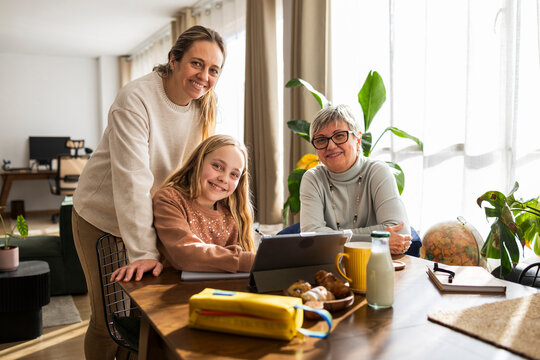 Girl doing homework on a tabletwith mother and grandmother assising