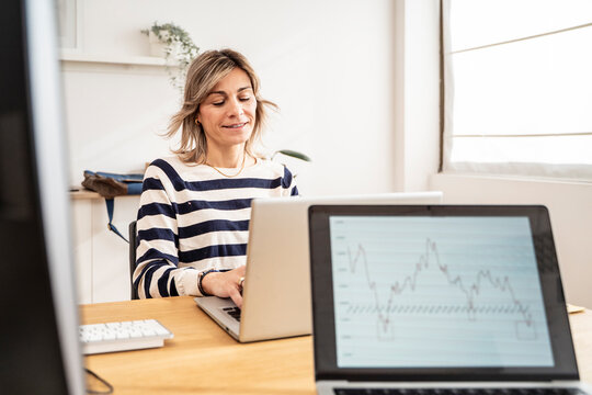 Businesswoman analyzing data on a laptop in an office - Powered by Adobe