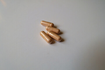 Close view of four pink capsules of palmitoylethanolamide dietary supplement