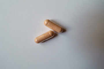 Close up of two pink capsules of palmitoylethanolamide dietary supplement