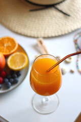 Glass of cocktail, straw hat, sunglasses, books, fresh fruit, chocolate and accessories. Summer essentials on the table. Selective focus.
