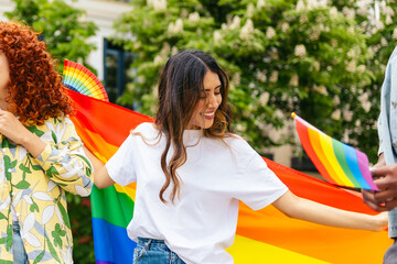 Young women holding rainbow flag celebrating lgbtqia plus pride month