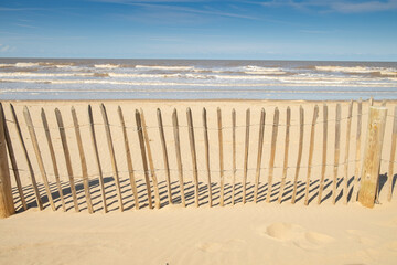 You can't stop the rising sea level or tide with cheap sea defenses - Fence across the beach at Formby, Merseyside, England,UK
