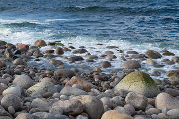Round stones on the edge of the Barents Sea on a March day. Teriberka. Murmansk region, Russia