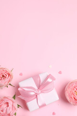 Beautiful pink peony roses with gift box on color background