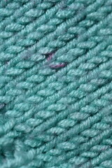 turquoise texture of knitted wool fabric as a background, teal smooth symmetrical lines of hand-knitted needlework pattern	
